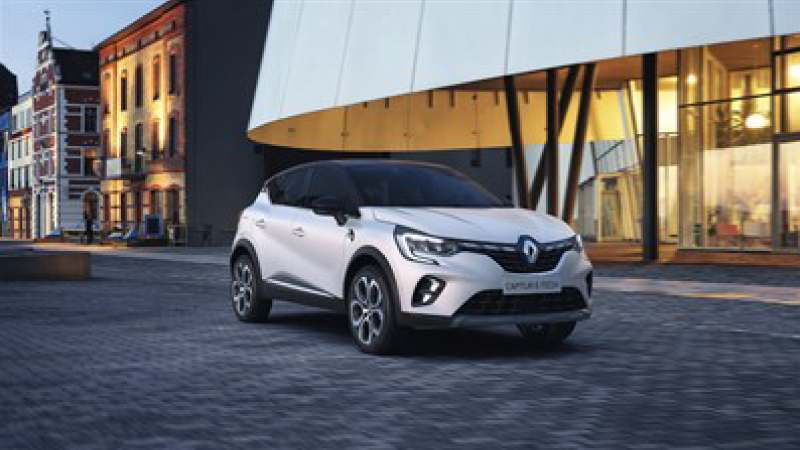 a white captur in a paved road in a city outside a big store