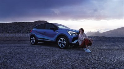 the front side of a renault captur and a woman standing infront of it