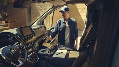 the inside of the renault new trafic and a man that putting some gloves in the glove box