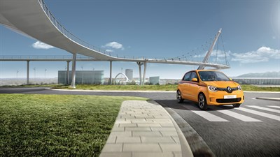 an orange renault twingo moving a big road with a bridge behind it